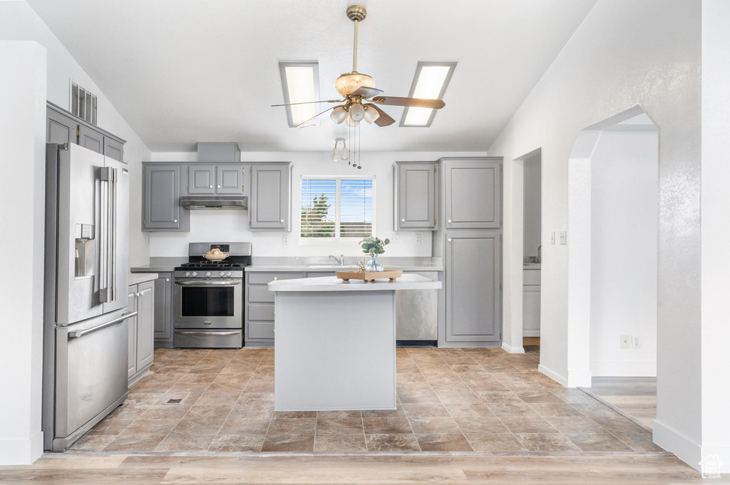 Kitchen featuring stainless steel appliances, gray cabinets, ceiling fan, a sink, and under cabinet range hood