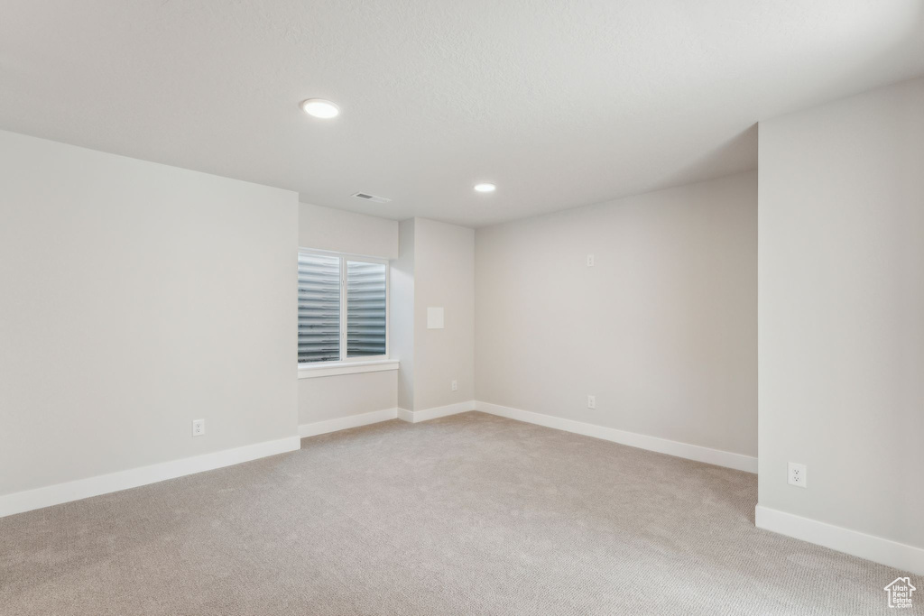 Spare room featuring light carpet, recessed lighting, and baseboards