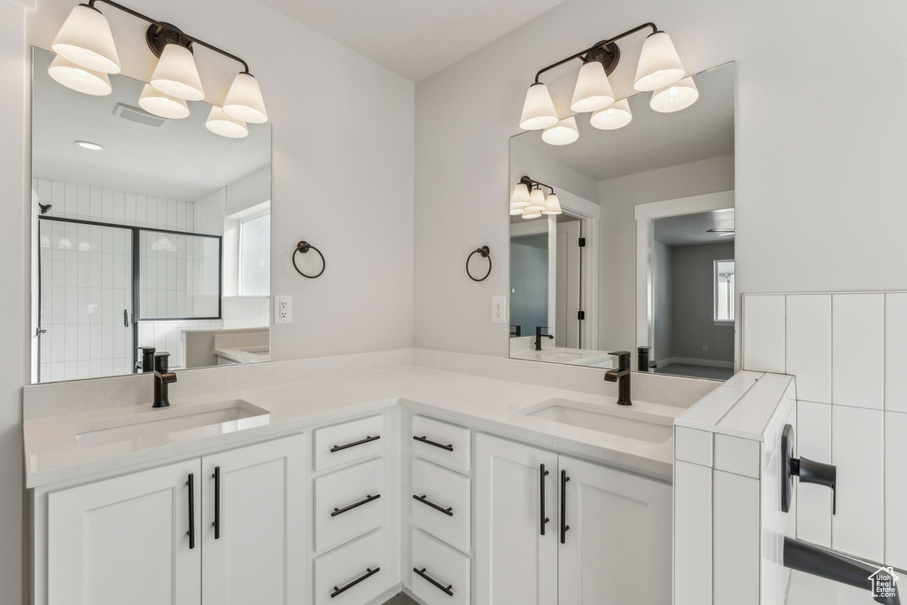 Bathroom featuring a shower stall and double vanity