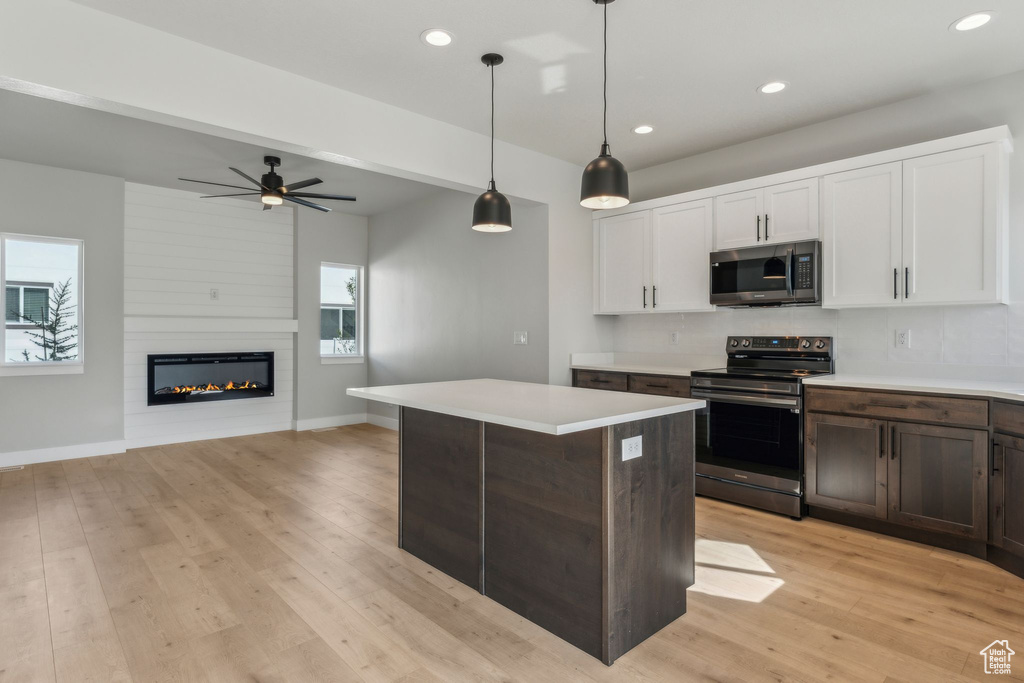 Kitchen with appliances with stainless steel finishes, light countertops, light wood-style floors, white cabinets, and recessed lighting