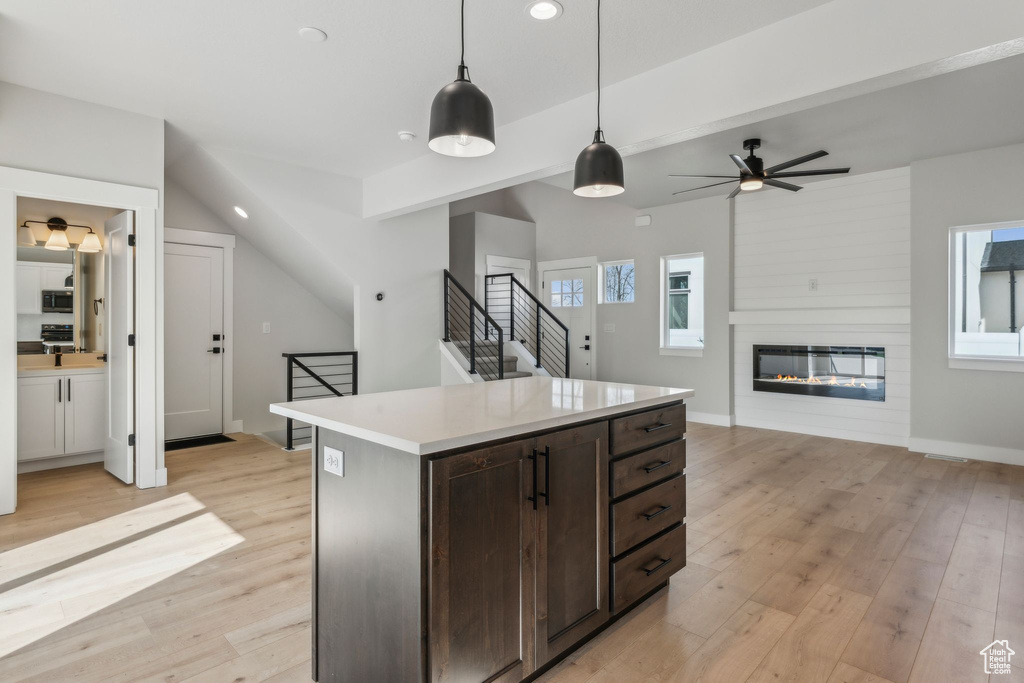 Kitchen featuring recessed lighting, stainless steel microwave, light wood-style flooring, decorative light fixtures, and light countertops