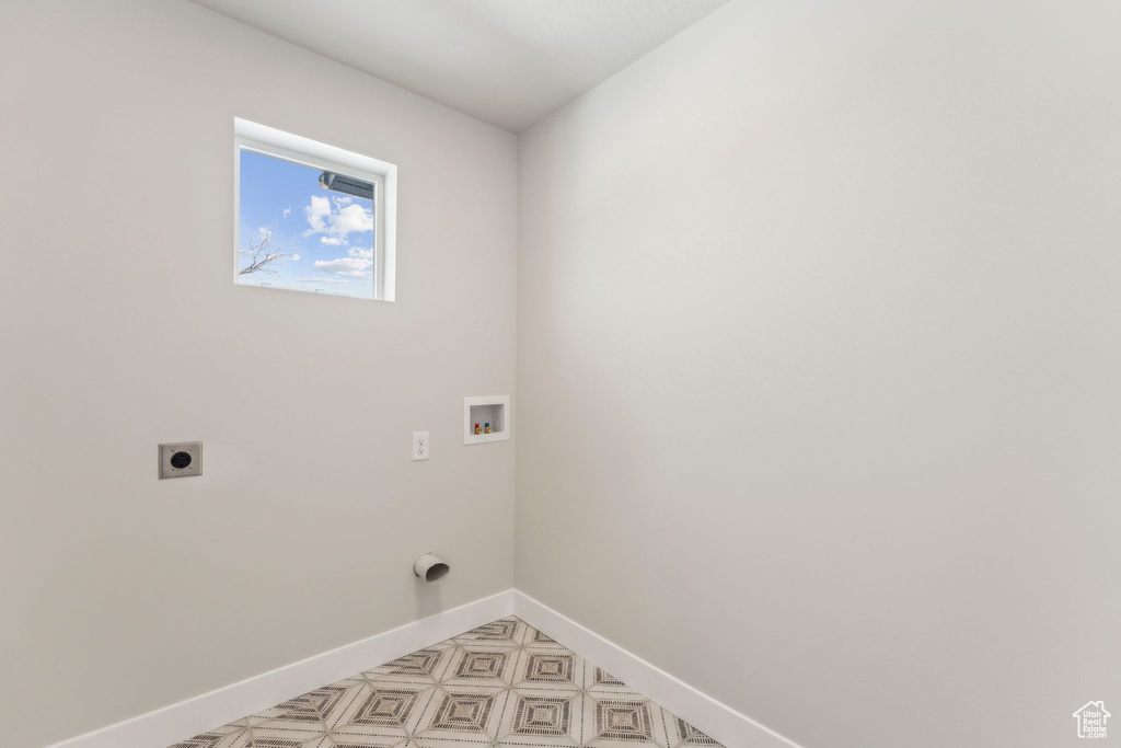 Clothes washing area featuring hookup for an electric dryer, washer hookup, and baseboards