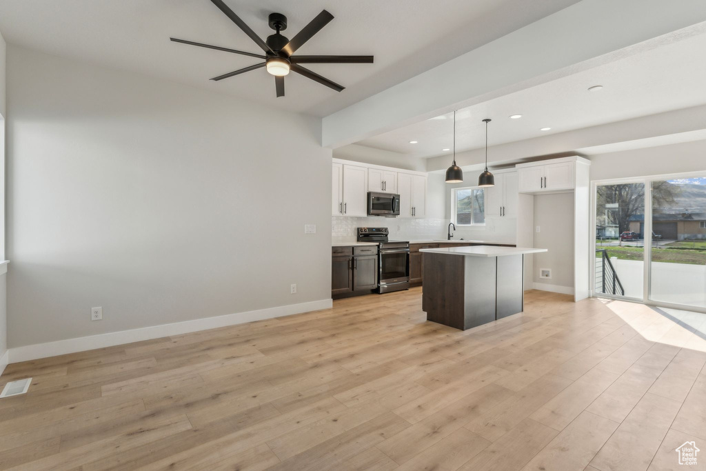 Kitchen featuring stainless steel appliances, a sink, white cabinetry, a kitchen island, and a ceiling fan