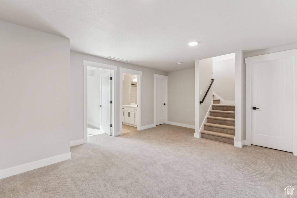 Below grade area with light carpet, baseboards, and stairs