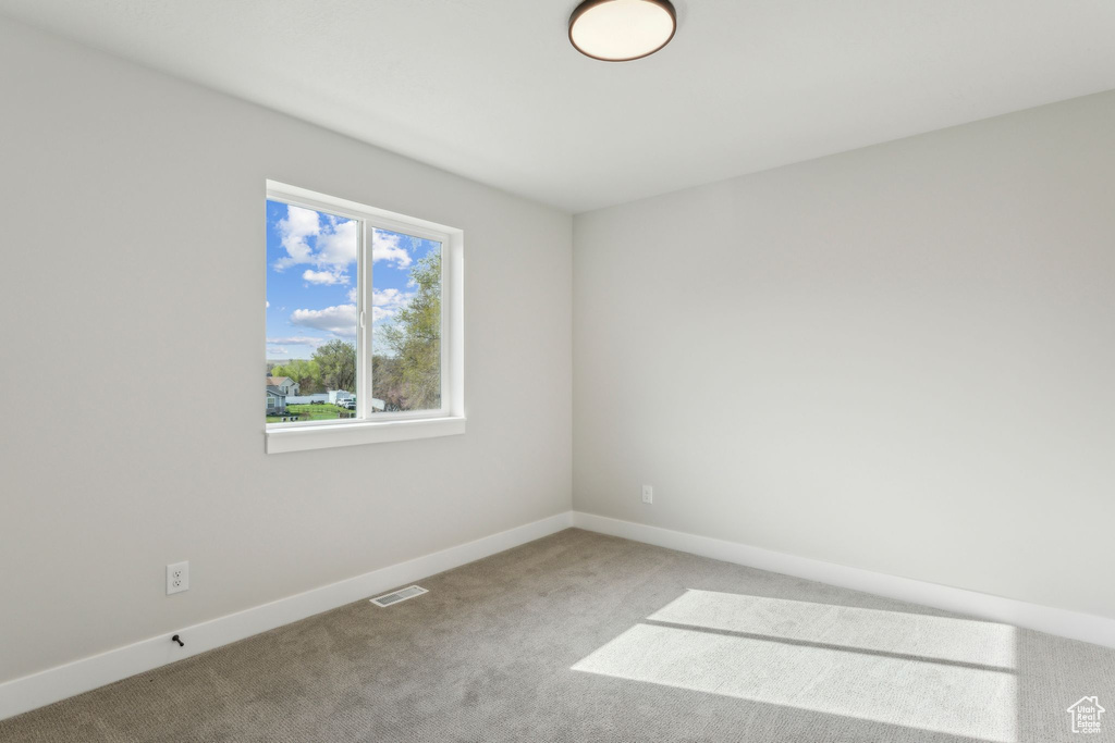 Carpeted spare room featuring baseboards