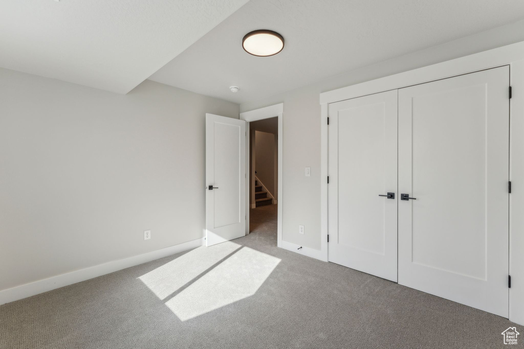 Unfurnished bedroom with carpet floors, baseboards, and a closet