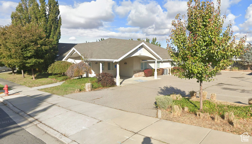 Ranch-style home featuring concrete driveway, covered porch, stucco siding, and a carport