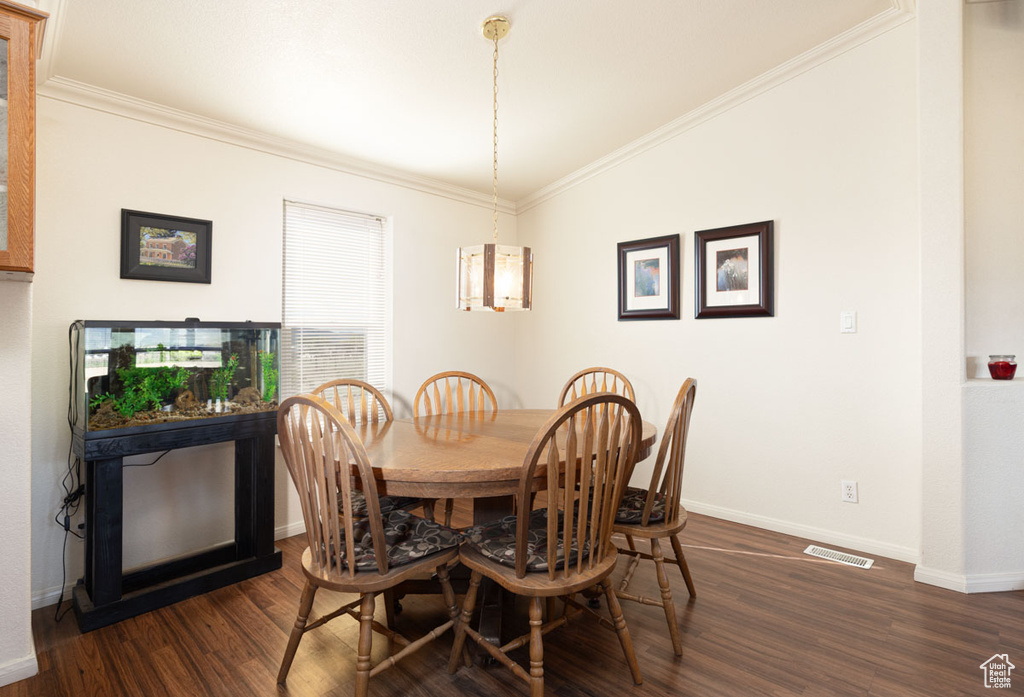 Dining area featuring dark wood-style floors, baseboards, and ornamental molding