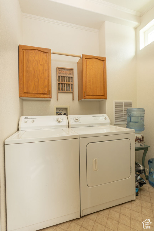 Laundry room with cabinet space, washing machine and dryer, and ornamental molding