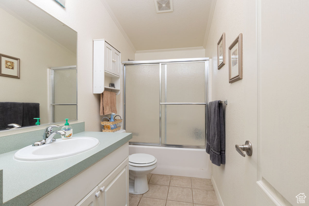 Full bathroom featuring ornamental molding, tile patterned floors, vanity, toilet, and shower / bath combination with glass door
