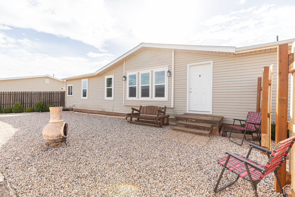 Rear view of house featuring fence and a fire pit