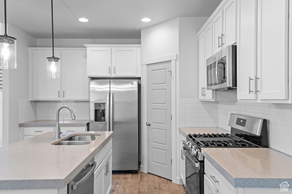 Kitchen with stainless steel appliances, a sink, an island with sink, recessed lighting, and light wood-type flooring