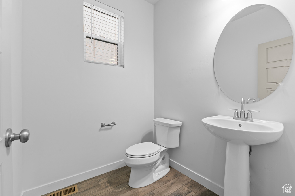 Half bathroom with toilet, baseboards, and wood finished floors