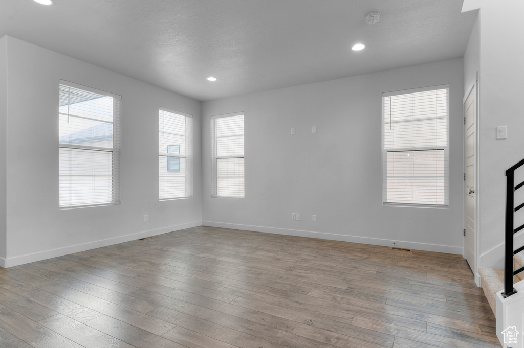 Unfurnished room featuring healthy amount of natural light, baseboards, wood finished floors, and recessed lighting
