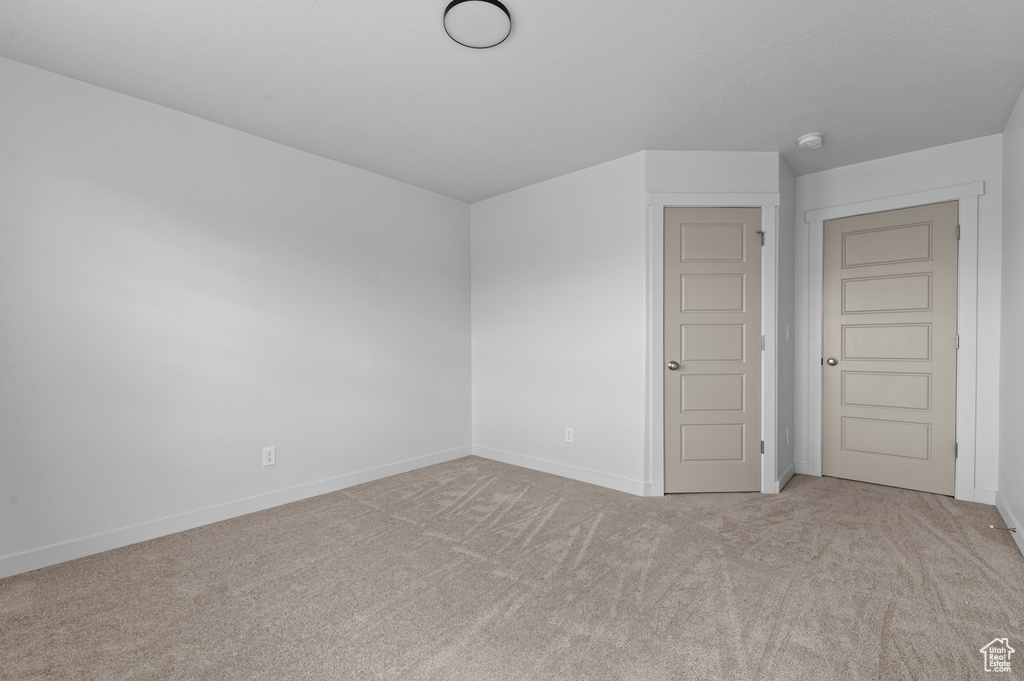 Carpeted spare room featuring baseboards and a smoke detector
