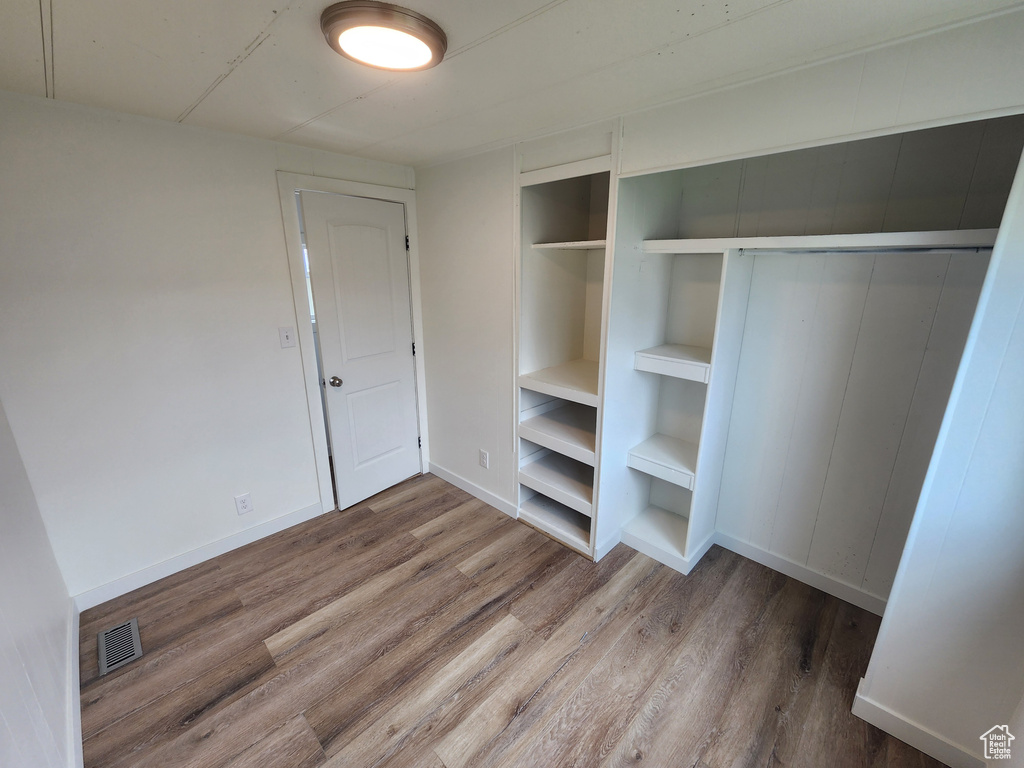 Unfurnished bedroom with wood finished floors, baseboards, and a closet