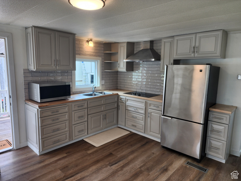 Kitchen with stainless steel appliances, wall chimney exhaust hood, a sink, and gray cabinetry