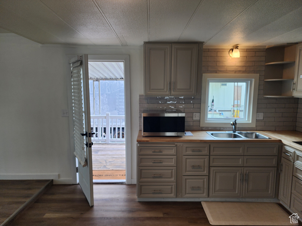 Kitchen with stainless steel microwave, a sink, dark wood-style floors, a textured ceiling, and light countertops