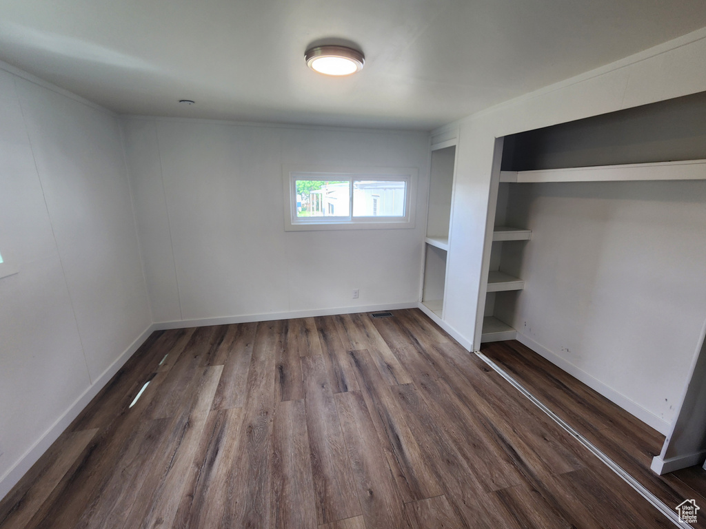 Unfurnished bedroom featuring dark wood-style floors and baseboards