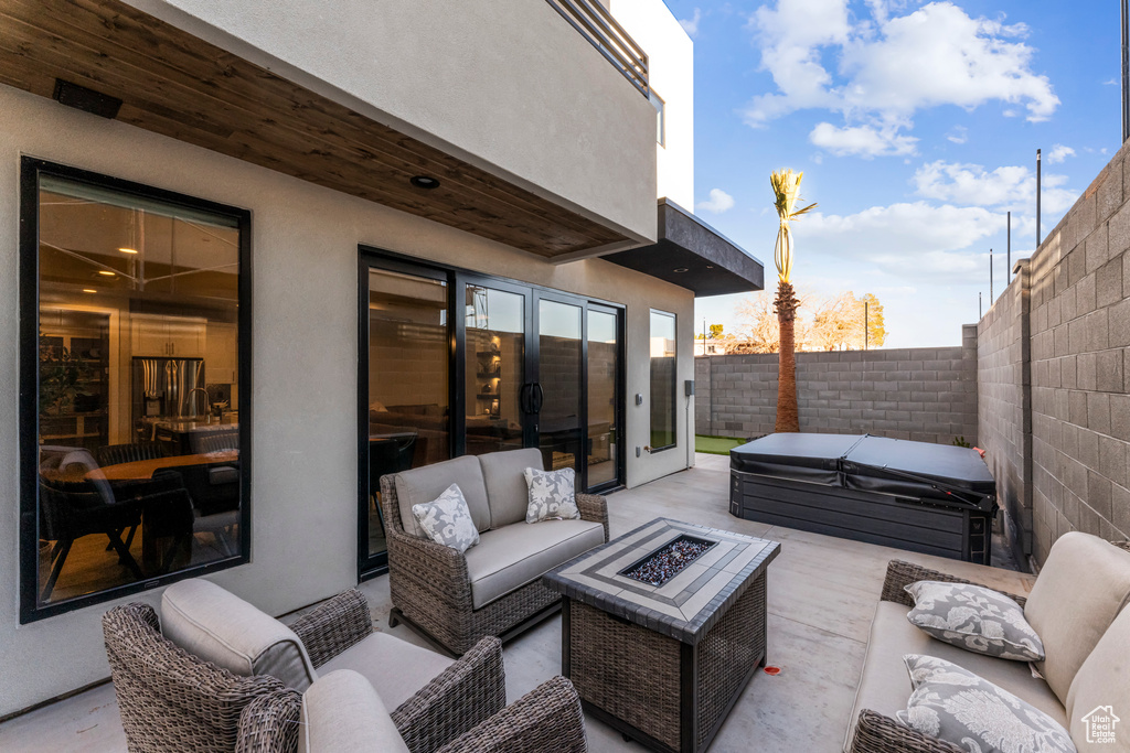 View of patio / terrace featuring a covered hot tub, an outdoor living space with a fire pit, and a fenced backyard