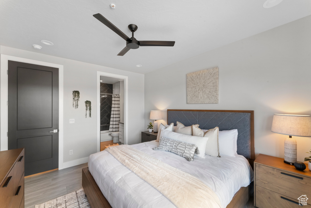 Bedroom featuring light wood finished floors, baseboards, connected bathroom, and ceiling fan