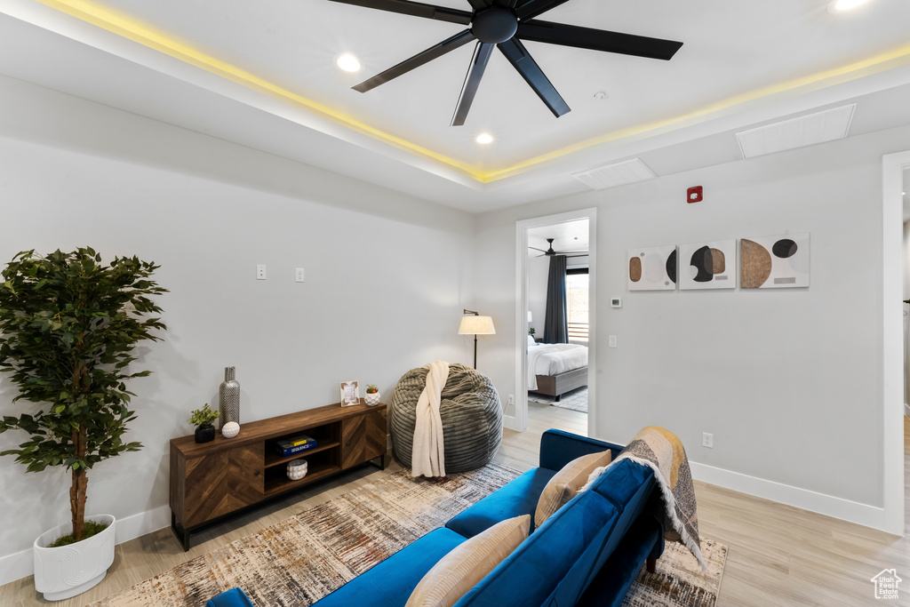 Living room featuring recessed lighting, a ceiling fan, baseboards, light wood finished floors, and a tray ceiling