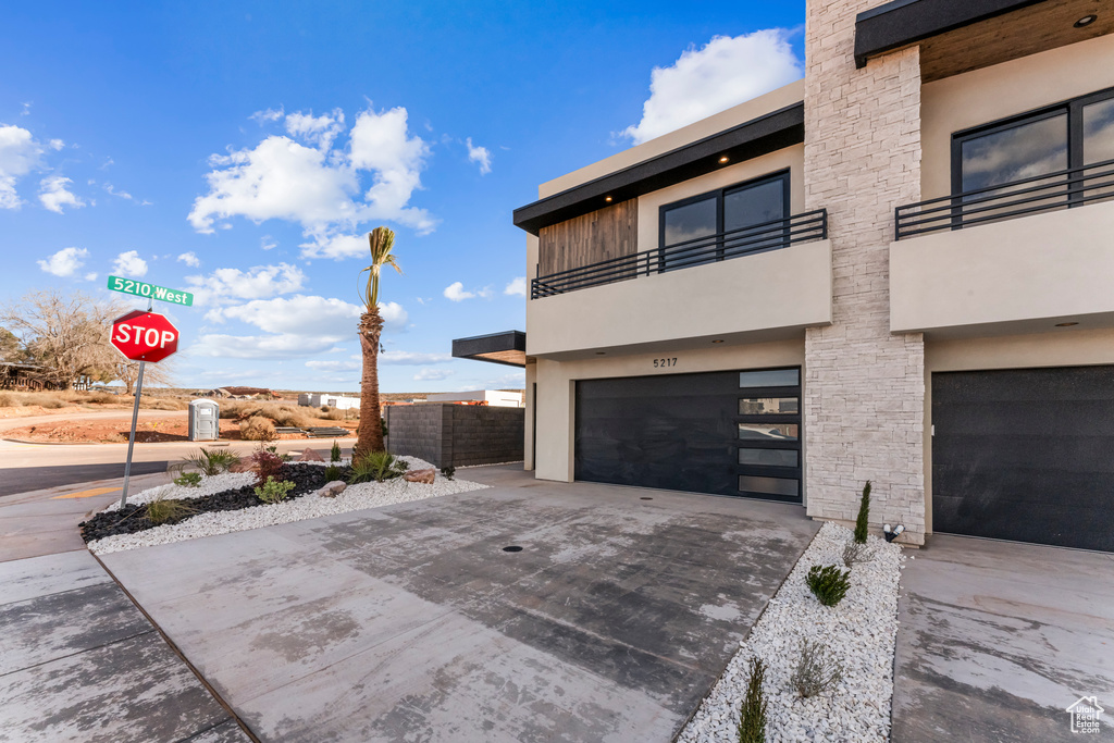 View of side of property with a balcony, concrete driveway, and an attached garage