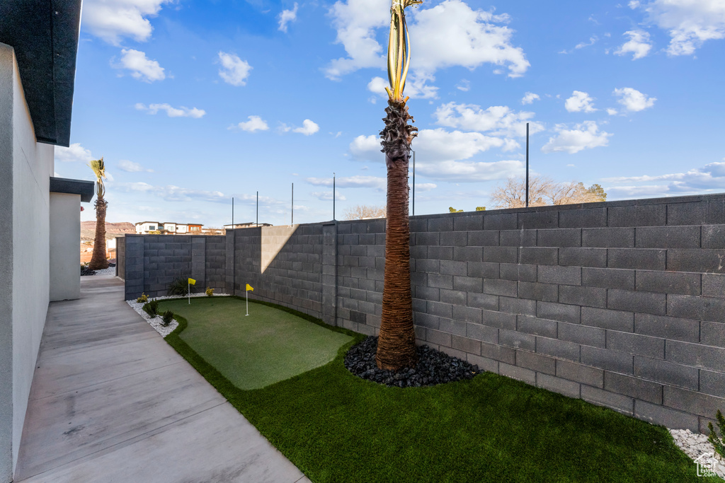 Fenced backyard featuring an area to practice putting