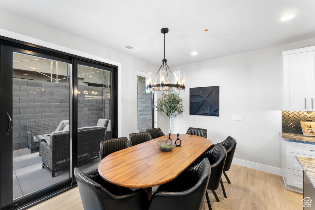 Dining area featuring light wood-type flooring, a chandelier, baseboards, and recessed lighting