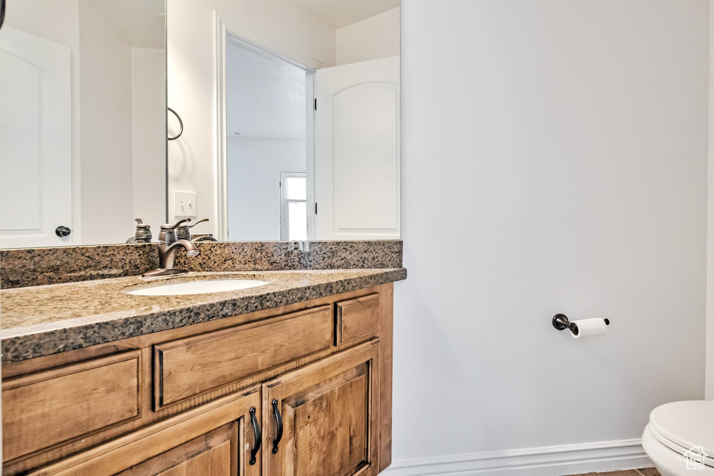 Bathroom featuring toilet, vanity, and baseboards