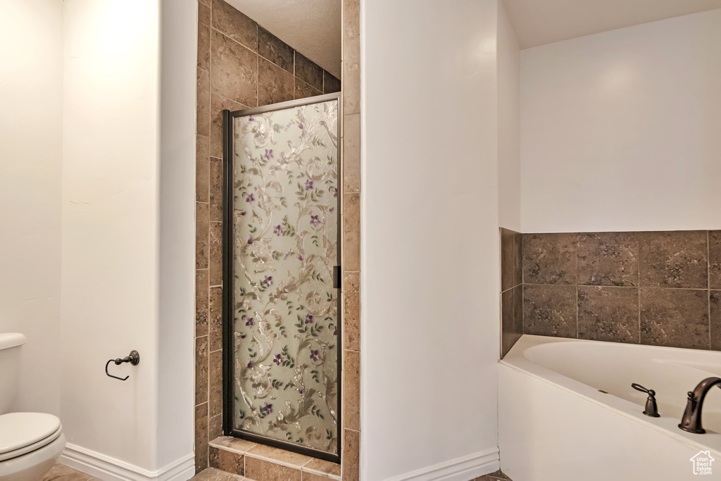Full bath with a shower stall, toilet, a garden tub, and baseboards