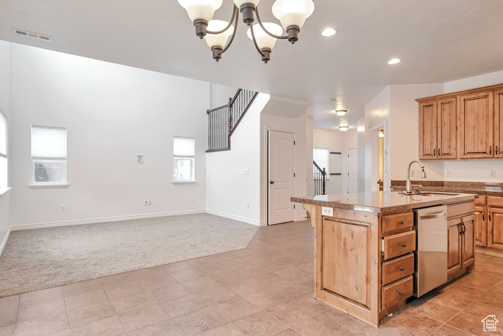 Kitchen with stainless steel dishwasher, light colored carpet, a sink, a chandelier, and a center island with sink