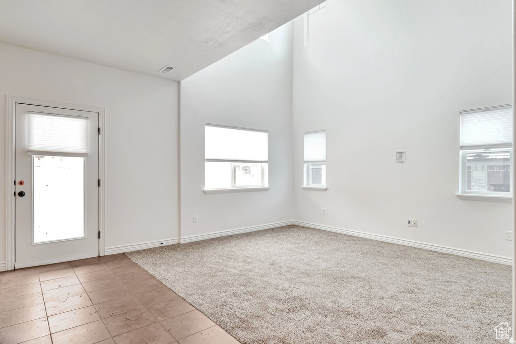Empty room featuring light colored carpet, baseboards, and light tile patterned floors