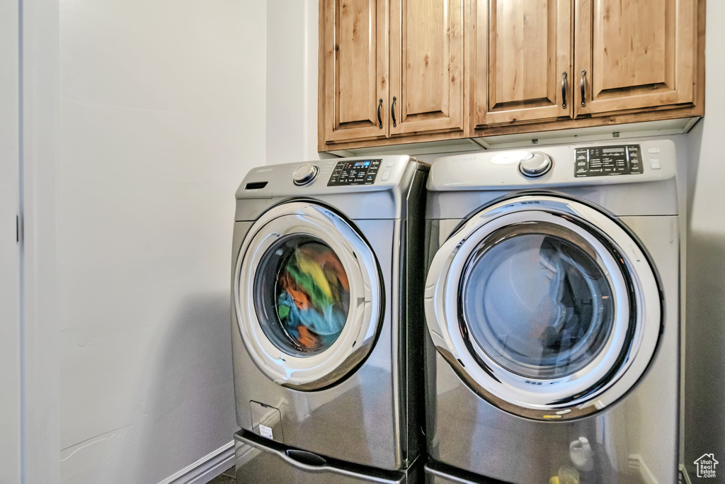 Laundry area with cabinet space, washer and dryer, and baseboards