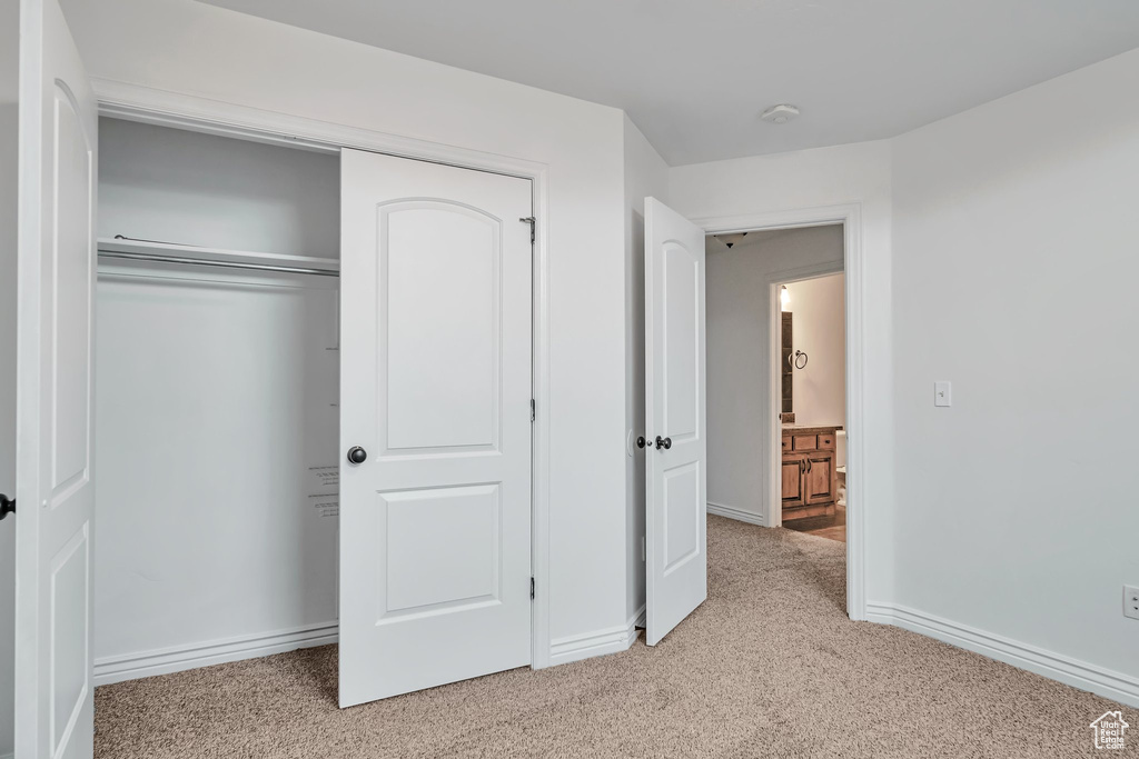 Unfurnished bedroom featuring light colored carpet, a closet, and baseboards