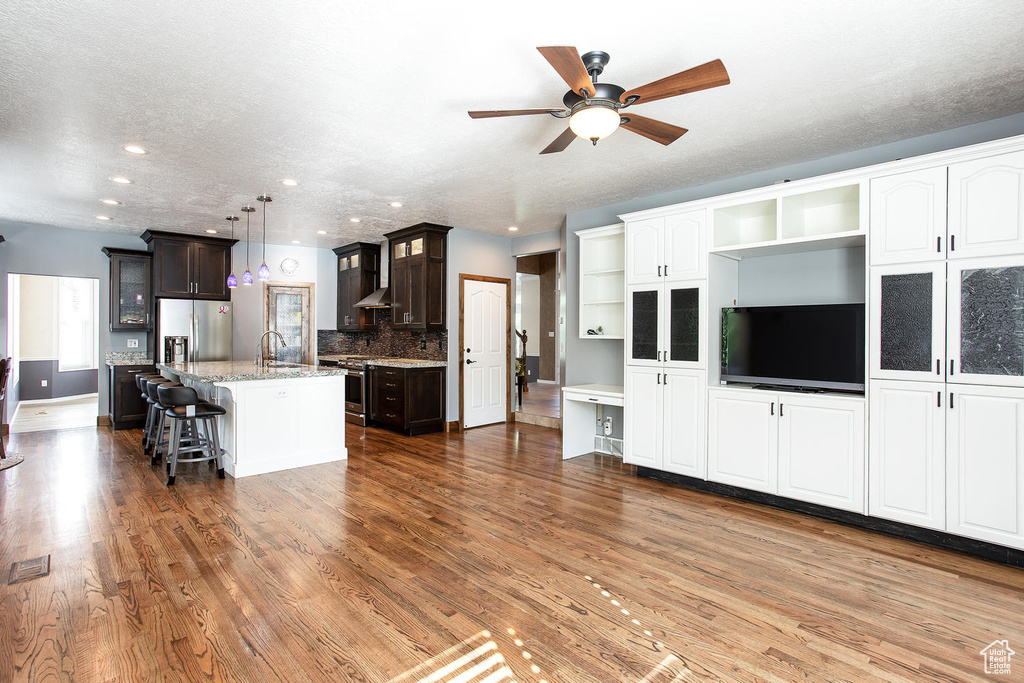 Living room with wood finished floors, ceiling fan, recessed lighting, and baseboards