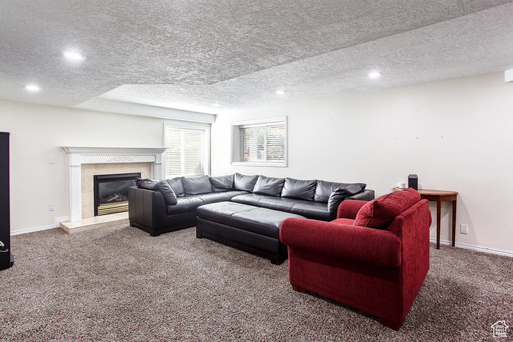 Carpeted living room featuring a textured ceiling, a tile fireplace, recessed lighting, and baseboards