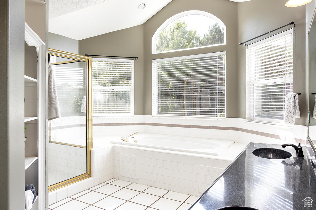 Bathroom featuring a bath, a shower stall, tile patterned floors, vanity, and vaulted ceiling