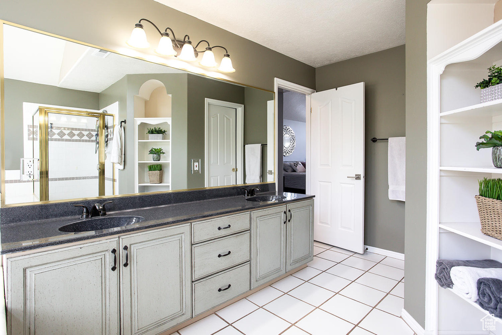 Full bath with tile patterned flooring, double vanity, a tile shower, baseboards, and built in features