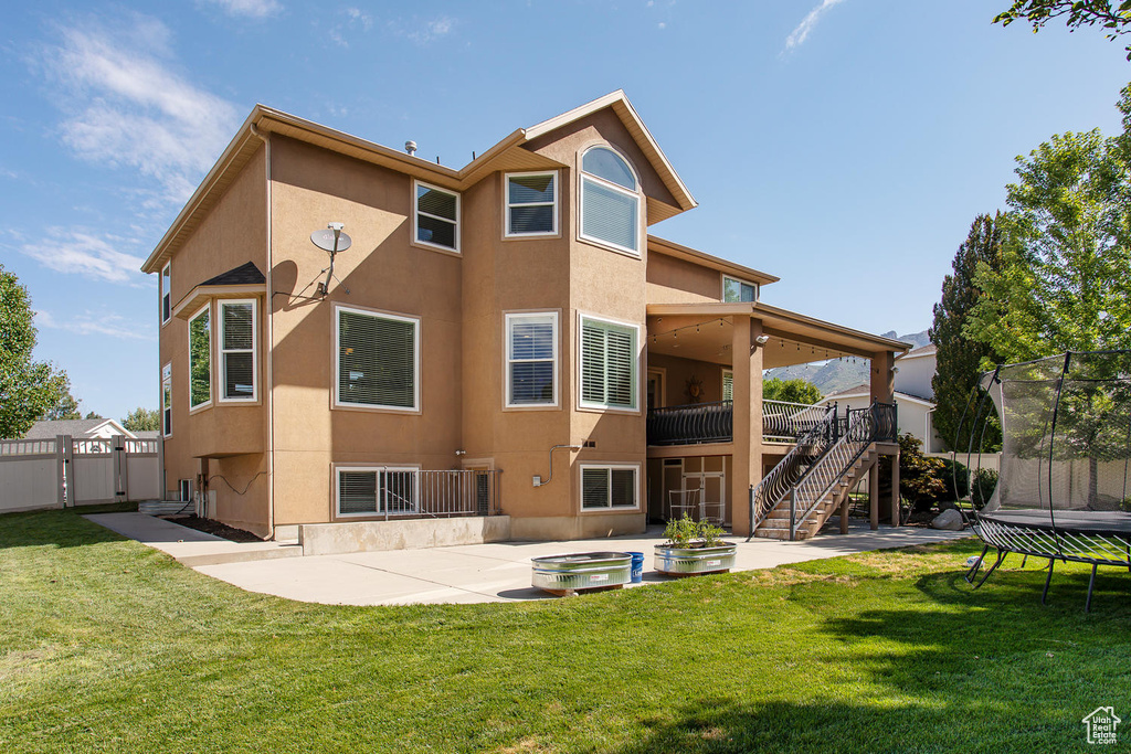 Back of house featuring a trampoline, a patio, stucco siding, and stairway