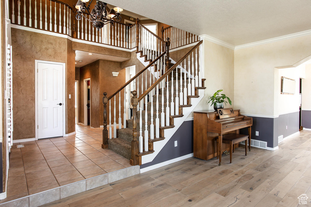 Stairway with baseboards, crown molding, a chandelier, and wood finished floors