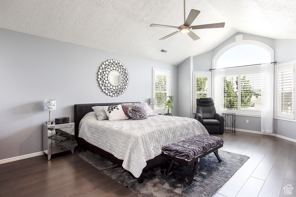 Bedroom featuring lofted ceiling, a textured ceiling, wood finished floors, a ceiling fan, and baseboards