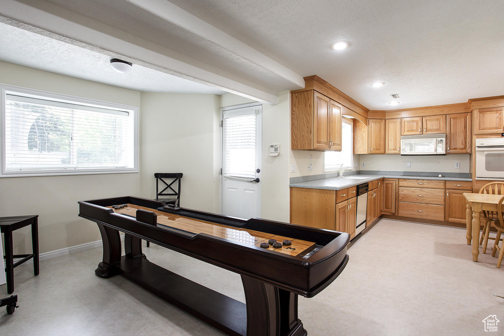 Kitchen with white appliances, a sink, plenty of natural light, light floors, and recessed lighting