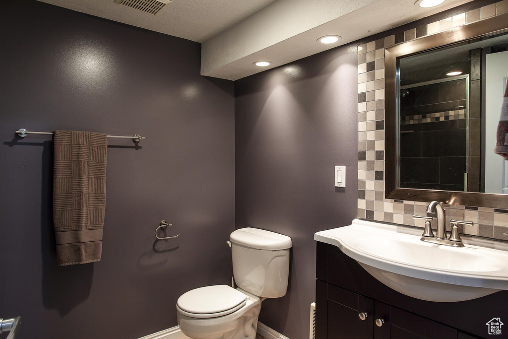 Bathroom with toilet, decorative backsplash, vanity, recessed lighting, and baseboards
