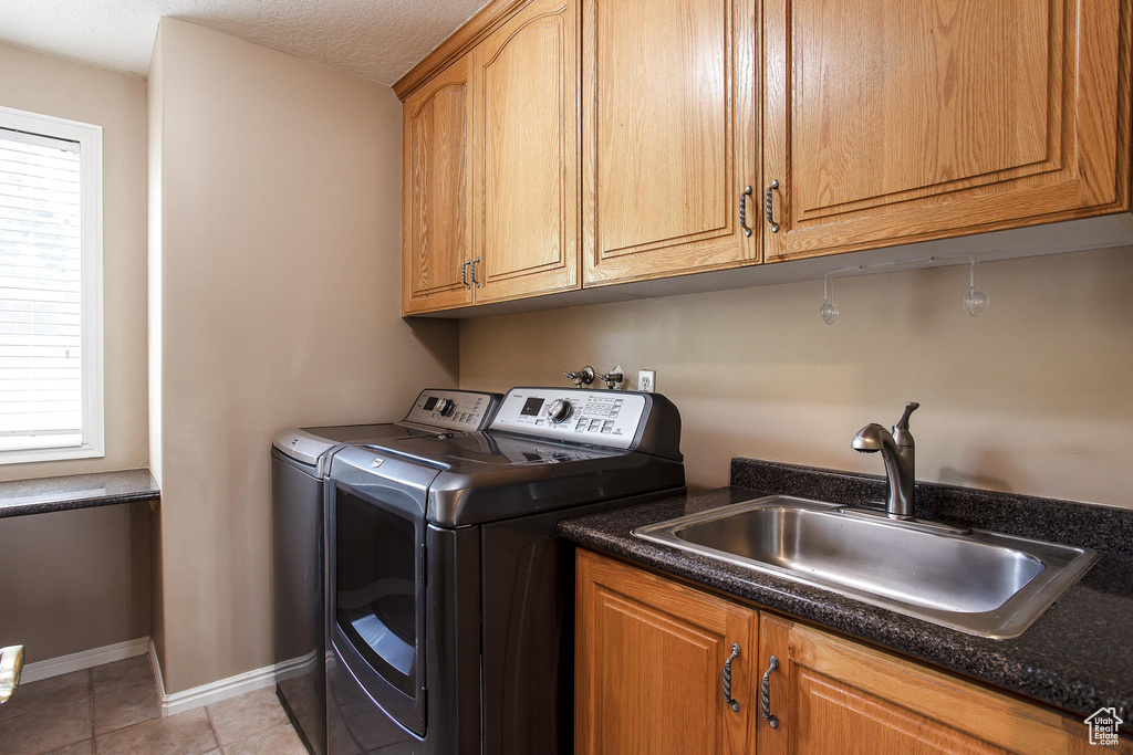 Laundry area featuring washing machine and dryer, cabinet space, plenty of natural light, and baseboards