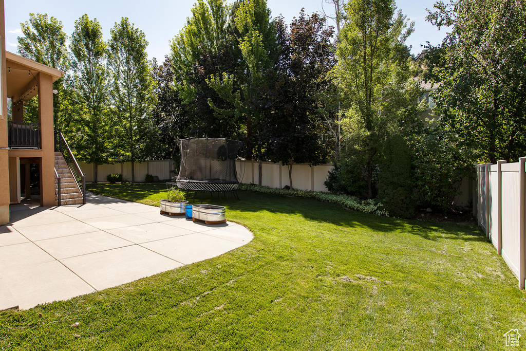 View of yard featuring a trampoline, a patio area, and stairs