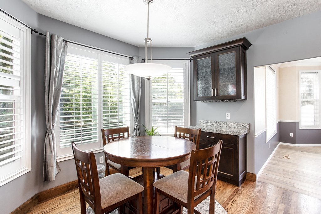 Dining area with light wood finished floors, baseboards, and a textured ceiling