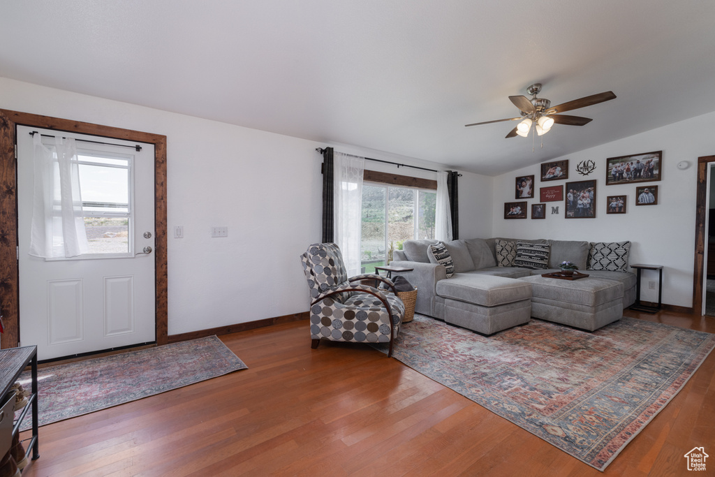 Living area with vaulted ceiling, a ceiling fan, wood finished floors, and baseboards