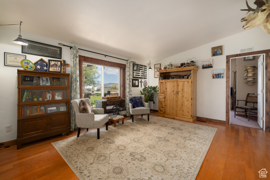 Sitting room featuring wood finished floors, lofted ceiling, and baseboards