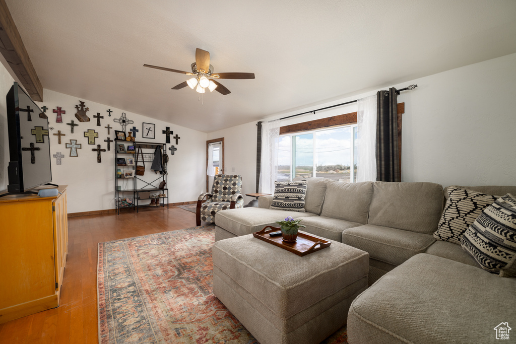 Living room with a ceiling fan, vaulted ceiling, wood finished floors, and baseboards